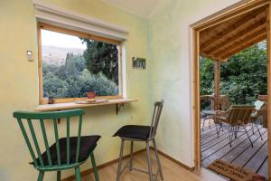 Zimmer mit Stühlen, einem Fenster und einer Veranda in der Unterkunft הפינה שלה -Hapina shella ראש פינה העתיקה in Rosch Pina
