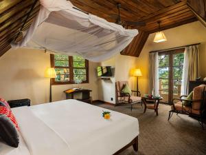 een slaapkamer met een groot bed en een woonkamer bij Ana Mandara Villas Dalat Resort & Spa in Da Lat