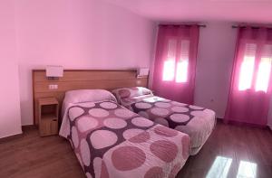2 camas en un dormitorio con cortinas rosas en ALOJAMIENTOS AGAVE, en Tabernas