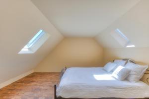 a attic bedroom with a bed with two skylights at Cap d'Eau in Waasmunster