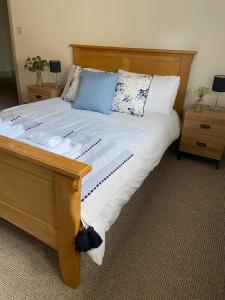 een groot bed met witte lakens en blauwe kussens bij Grade II Listed 3 Bedroom Cottage With Free Parking in Kings Lynn