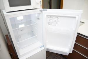 een witte koelkast met open deur en een magnetron bij NY Cottage B in Tokyo