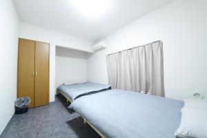 een slaapkamer met 2 bedden en een kast bij NY Cottage B in Tokyo