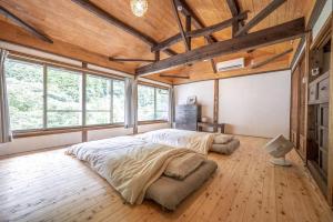 a bedroom with a large bed in a room with windows at 古民家一棟貸し宿　山のめぐみ舎 in Niyodogawa