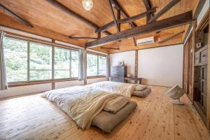 1 dormitorio con 1 cama grande en una habitación con ventanas en 古民家一棟貸し宿　山のめぐみ舎, en Niyodogawa