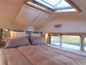 a large bed in a room with a window at BellaTiny, Tiny House & Gypsy Wagon in Ondekaremba