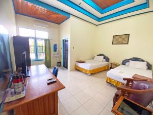 a room with two beds and a desk in a room at Capital O 91806 Hotel Batu Suli in Palangkaraya