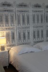 a bedroom with a white bed with a wall at Hotel Le XIV in Pontorson