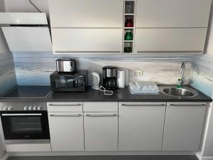Una cocina con gabinetes blancos y un fregadero. en Bungalow "Vera", en Ostseebad Koserow