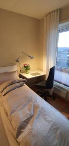 a bedroom with a bed and a desk with a vase of flowers at Spacious Fornebu apartment near the sea in Fornebu