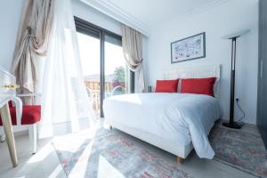 a bedroom with a white bed with red pillows and a window at Villa Palmeraie Golf Agadir in Agadir