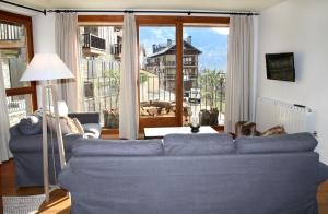 a living room with a blue couch and a large window at Apartaments Lo Paller in Valencia de Aneu