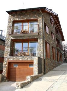 a brick building with a garage door and a balcony at Apartaments Lo Paller in Valencia de Aneu