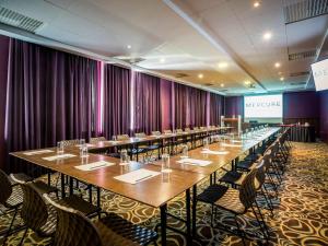 a row of tables and chairs in a room with purple curtains at Mercure Riga Centre in Rīga