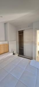 um quarto branco com uma cama grande e uma janela em Ático Corazones em Granada