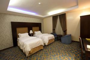 a hotel room with two beds and a desk at قصر اليمامة للشقق المخدومة Al Yamama Palace Serviced Apartments in Yanbu
