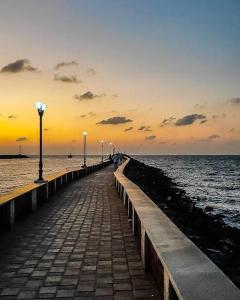 a pier leading to the ocean at sunset at Malpe Gruham Homestay Udupi in Malpe