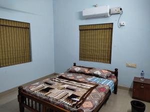 a bedroom with a bed with a fan and windows at Malpe Gruham Homestay Udupi in Malpe