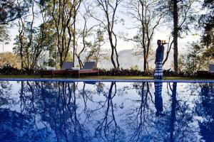 a man is standing next to a swimming pool at Ceylon Tea Trails in Hatton