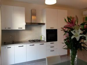 uma cozinha com armários brancos e um vaso de flores em Esclusivo appartamento alle Dune! Dalla piscina alla spiaggia in 30 mt! em Silvi Paese