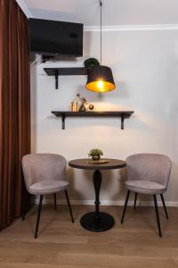 Habitación con 2 sillas, mesa y TV. en Apáca 30 Apartman **** Győr en Győr