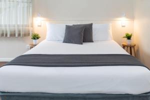 um quarto com uma cama grande com lençóis brancos e almofadas em Pacific Motel 06 em Forster