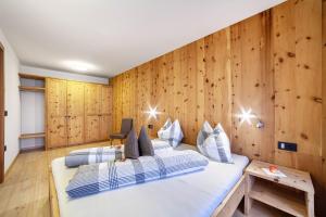 a bedroom with two beds and a wooden wall at Residence Kalchgruberhof Lärche in Ultimo