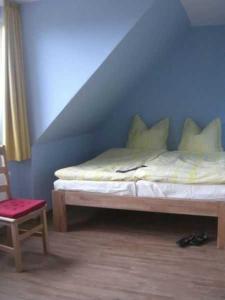 uma cama num quarto com uma cadeira e uma parede azul em Balm Haus Am Balmer See Haus 1 WBH1 em Balm