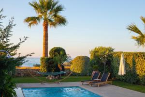 una piscina con due sedie e una palma di Villa Mathios a Pigianos Kampos