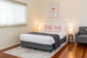 ein Schlafzimmer mit einem Bett mit rosa Kissen und einem Stuhl in der Unterkunft Pacific Motel 08 in Forster