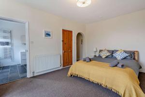 a bedroom with a bed and a door to a bathroom at Dizzy Heights Swanage Sleeps 10 with Amazing Views in Swanage