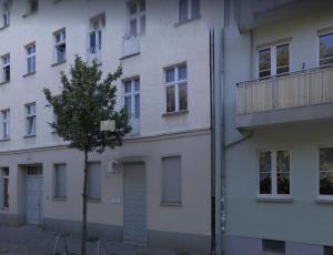 a white building with a tree in front of it at Central Lichtenberger Apartment for 6 People in Berlin