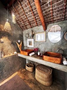 a bathroom with a wooden tub and two baskets at Mar-Me-Quer, Eco Beach Retreat in Inhambane