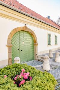 a green garage door on a building with pink flowers at Dunakavics XIII Apartman in Szentendre