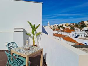 een tafel en stoelen op een balkon met uitzicht op een stad bij CASINHA DE FERRAGUDO - Terraço Privado, AC, WiFi, Centro 250m in Ferragudo