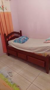 ein kleines Bett mit einem Holzrahmen in einem Zimmer in der Unterkunft Recanto dos Jardim's Arraial do Cabo in Arraial do Cabo