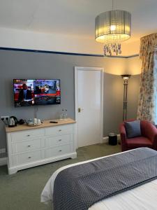 a bedroom with a bed and a tv on the wall at Glendower House in Minehead