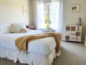 een slaapkamer met een wit bed met een deken erop bij Scenic Villa -Second Storey in Lake Hume