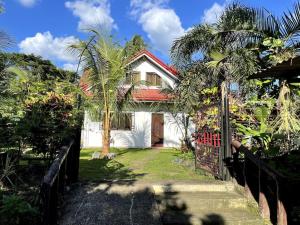 a white house with a red roof and a gate at Charming 3-Bedroom Country Farm Home Pool ParkSprings Lipa in Lipa