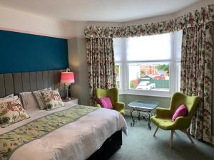 a bedroom with a bed and two chairs and a window at Glendower House in Minehead