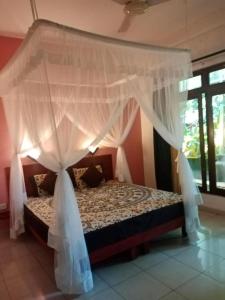 Villa Bentota River View في ألوثغاما: غرفة نوم مع سرير مظلة مع ستائر بيضاء