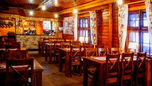 シュクラルスカ・ポレンバにあるGospoda Graniczna Bombaj Jakuszyceの木製のテーブルと椅子、窓のあるレストラン