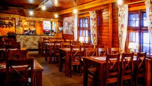 a restaurant with wooden tables and chairs and windows at Gospoda Graniczna Bombaj Jakuszyce in Szklarska Poręba