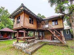 una casa en el árbol con un porche y escaleras a ella en OYO 91830 Hotel Gemilang 2, en Lombok