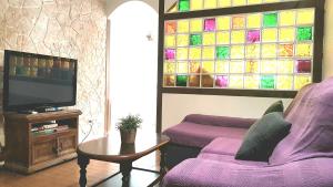 un salon avec un canapé violet et une télévision dans l'établissement Casa Alegre Estepona, à Estepona