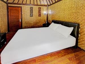 een groot wit bed in een kamer met een deur bij OYO 91830 Hotel Gemilang 2 in Lombok