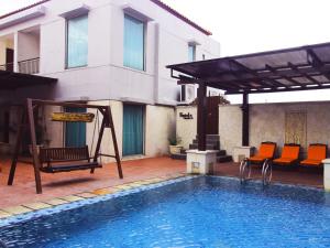 a swimming pool with a swing and a chair next to a house at Grand Surya Hotel Kediri in Kediri