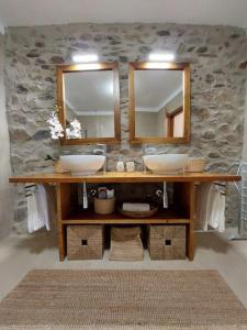 a bathroom with two sinks and a stone wall at Casa Férias Retiro do Rodeiras in Figueira de Castelo Rodrigo