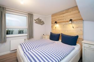 een slaapkamer met een bed met blauwe kussens en een raam bij Wattperle in Rantum