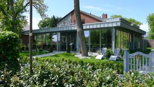 a house with a conservatory with a garden at Hotel Leegerpark in Greetsiel
